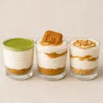 Three layered dessert cups with matcha, Biscoff, and protein cheesecake variations in clear glasses on a neutral background